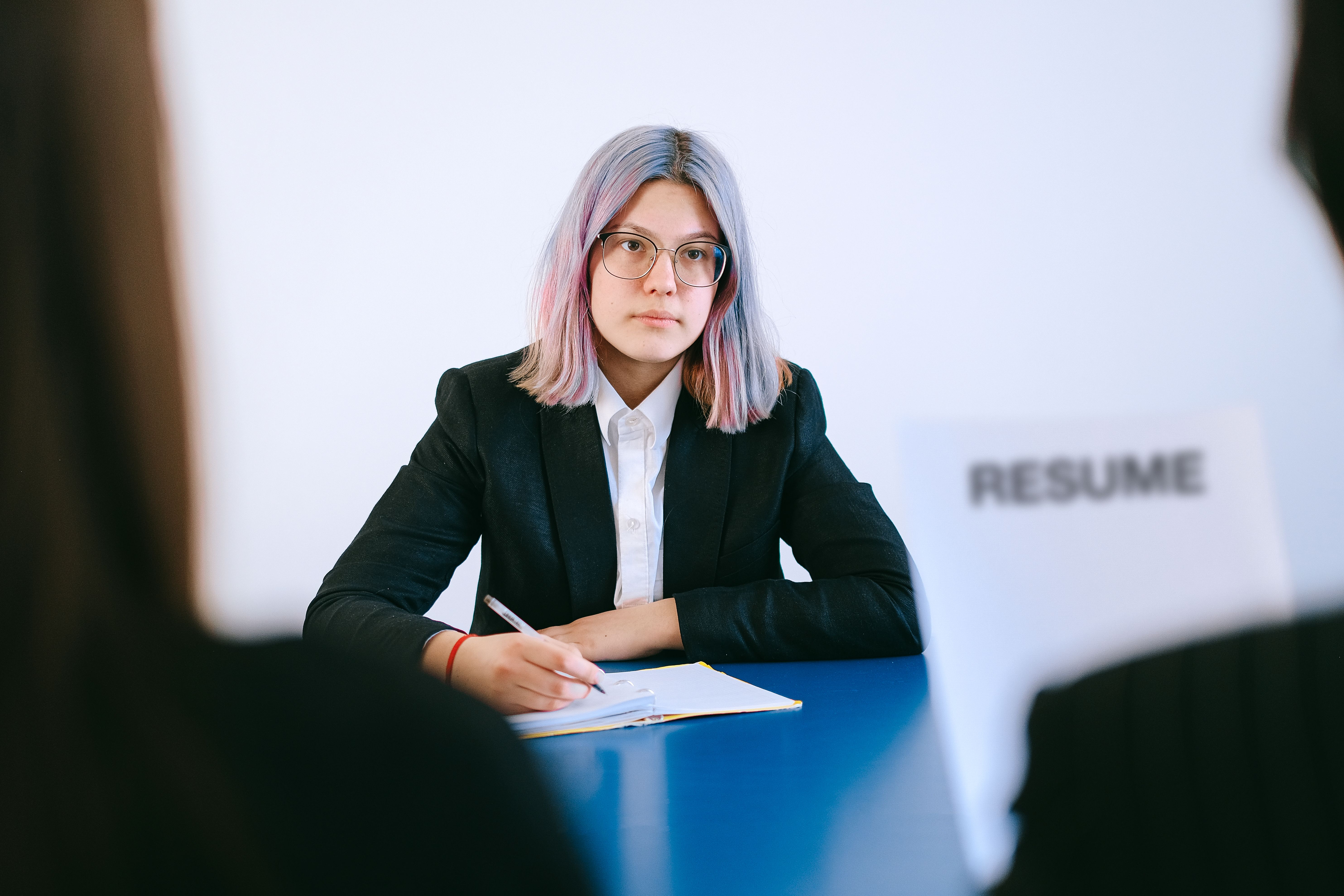 Young woman in a suit during a job interview, writing notes, representing recruitment screening