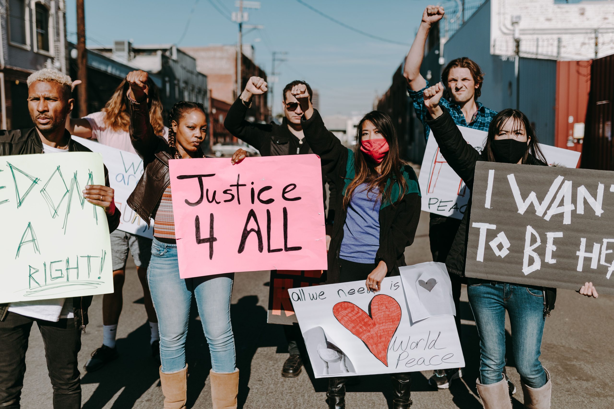 Diverse group of people holding protest signs for justice and equality, representing consumers banding together in a class action lawsuit