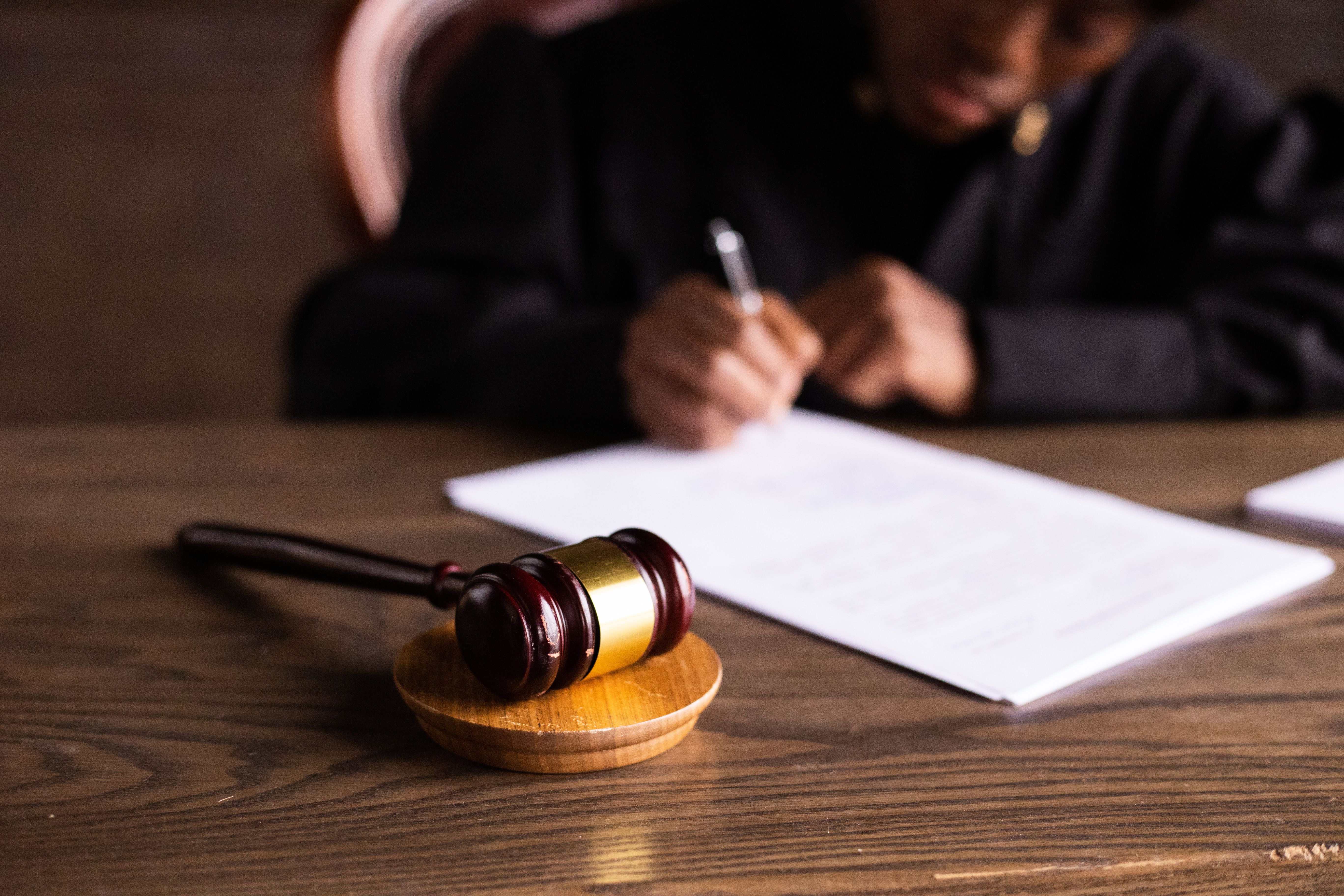 Judge signing legal documents beside a gavel during a class action lawsuit settlement