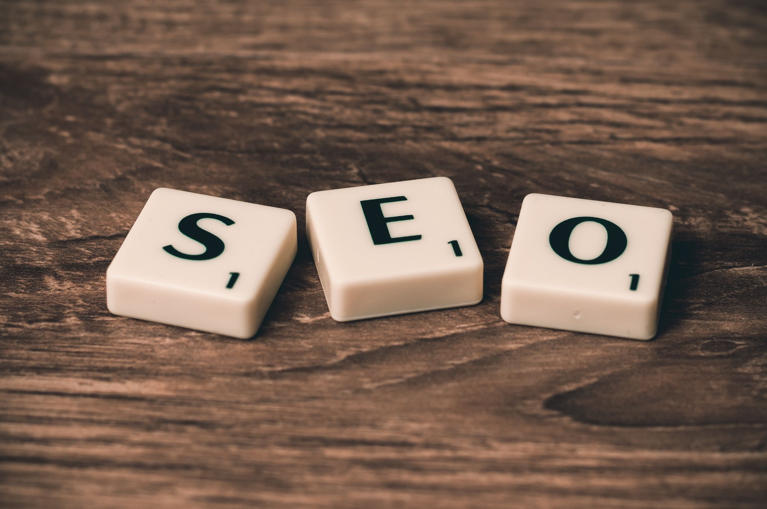 Scrabble tiles spelling SEO on a wooden table representing the search engine optimization industry